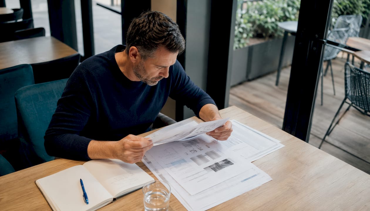 Un diagnostiqueur immobilier en train d’analyser un devis pour un DPE posé sur la table d’une maison.
