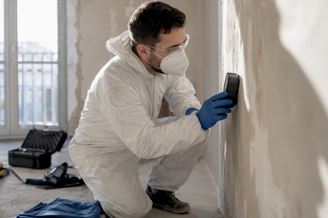 Diagnostiqueur plomb en action sur un mur de chantier